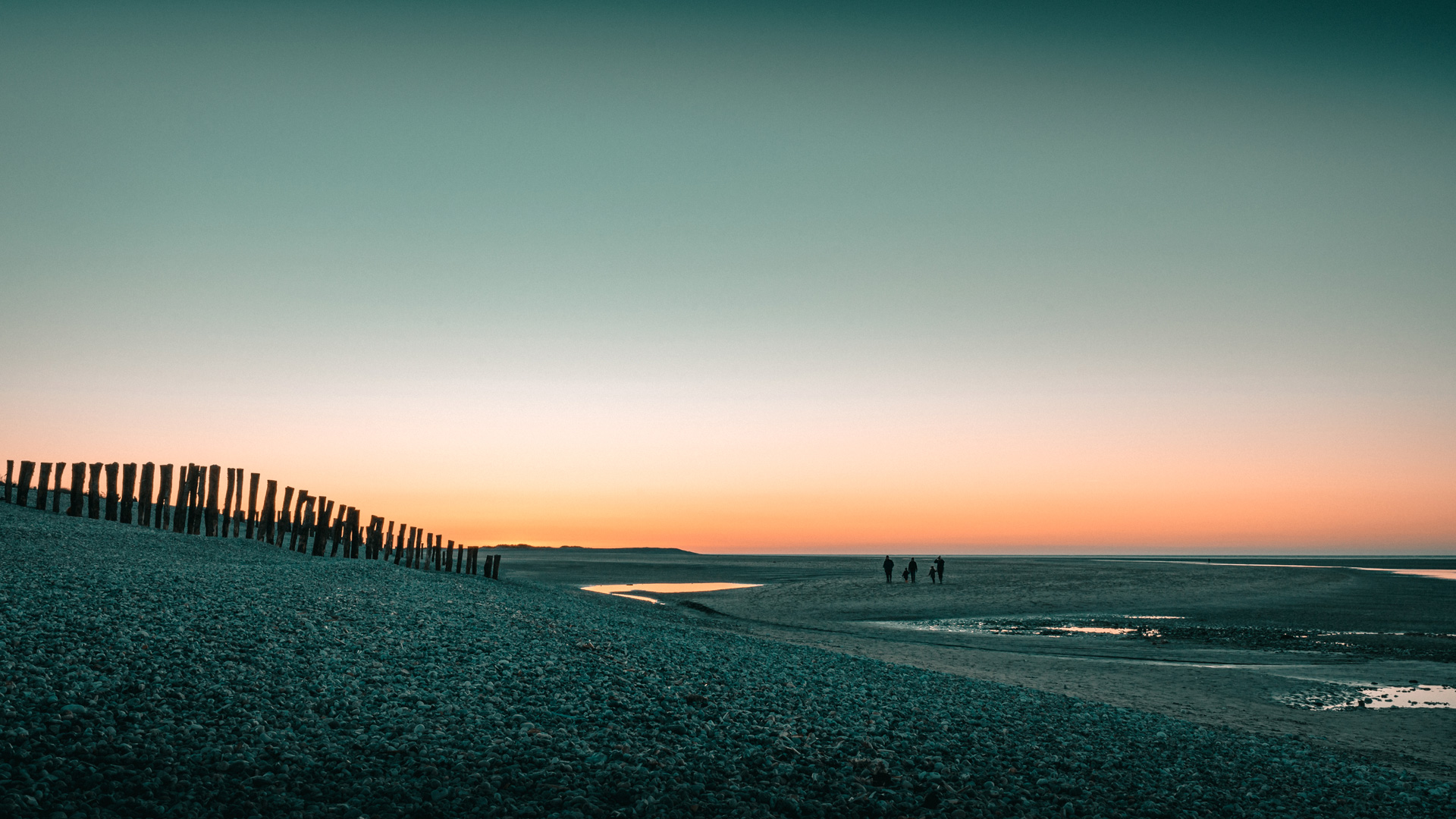 photo de plage au coucher de soleil avec une famille au loin