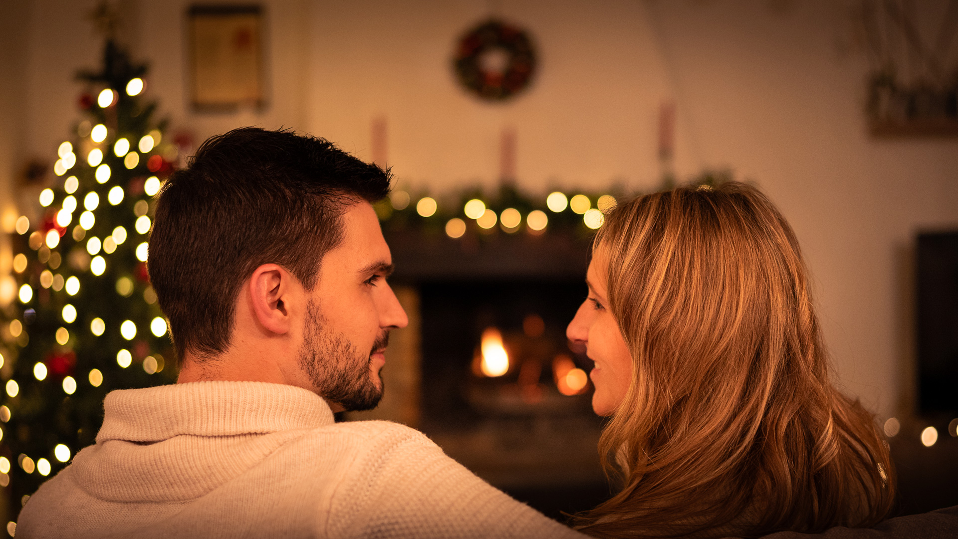 photo d'un couple pendant Noël dans une pièce décorée sur un canapé